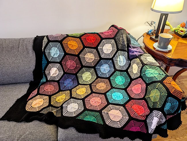 The blanket draped across the corner of a couch.