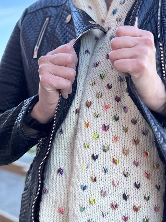 A closeup on the torso of the person wearing the scarf with the scarf draped around her neck. She's pulling her jacket closed around it.